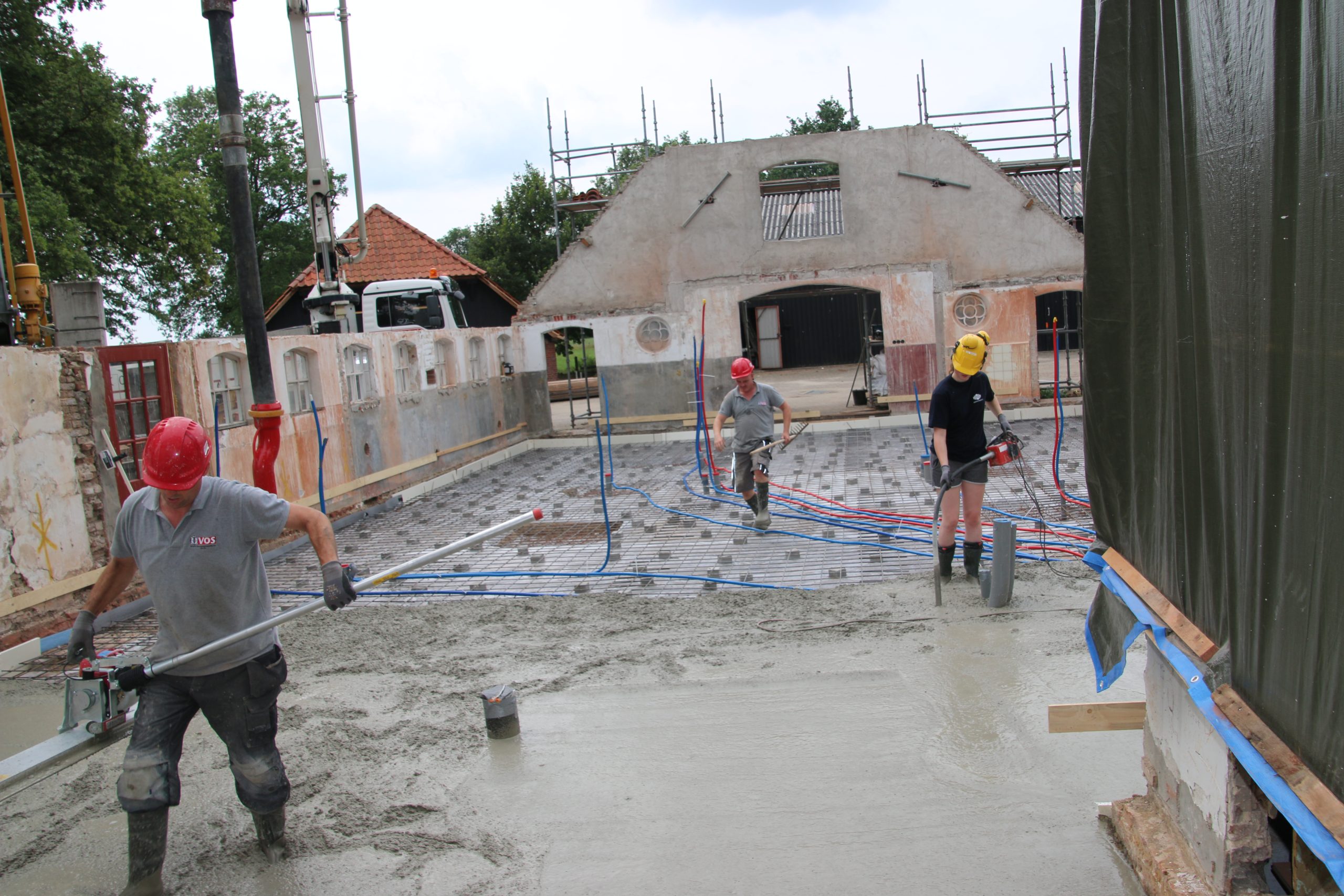 Bouwvakkers storten en vlinderen betonvloer in gerenoveerde schuur.